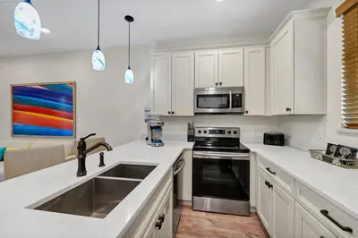 a white kitchen with a sink and a microwave at Dreamy Coral Cottage With Hot Tub Near Disney With Margaritaville Resort & Island H2O Waterpark Access - 3062Pi in Orlando