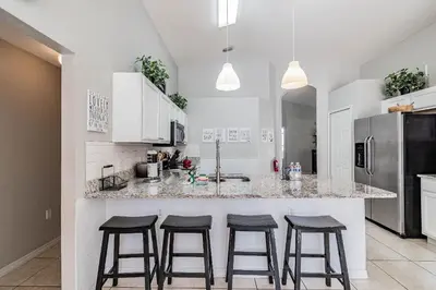 a kitchen with a counter with four bar stools at Casa Térrea 5Q c/ Piscina — 15min da Disney in Kissimmee