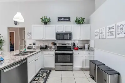 a kitchen with white cabinets and a stove top oven at Casa Térrea 5Q c/ Piscina — 15min da Disney in Kissimmee