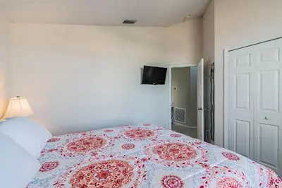 a bedroom with a bed with a flowered blanket on it at Casa Térrea 5Q c/ Piscina — 15min da Disney in Kissimmee