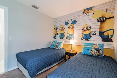 a bedroom with two beds and a wall with minions at Casa Térrea 5Q c/ Piscina — 15min da Disney in Kissimmee