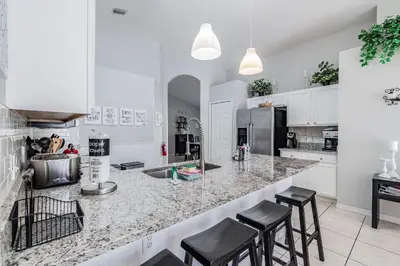 a kitchen with a marble counter top and stools at Casa Térrea 5Q c/ Piscina — 15min da Disney in Kissimmee