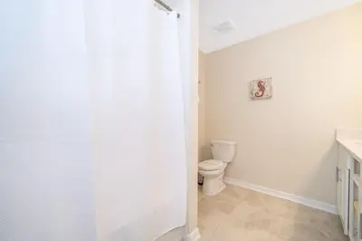a bathroom with a toilet and a shower curtain at Modern Condo Near Disney in Kissimmee