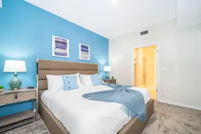 a bedroom with a large bed with blue walls at Modern Condo Near Disney in Kissimmee