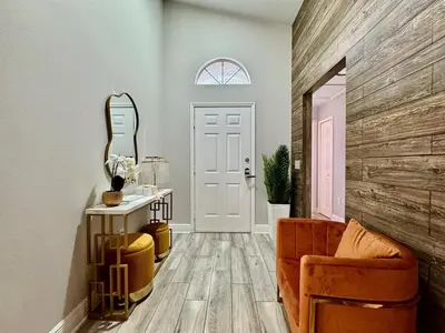 a living room with a mirror and a chair at Modern 4BR 2BA with pool in gated community in Kissimmee
