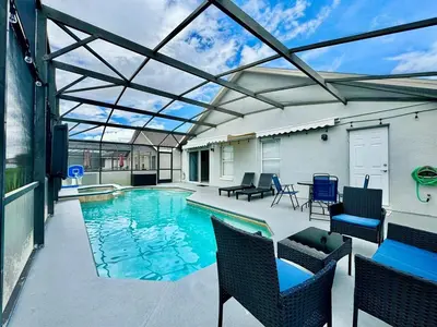 a patio with a swimming pool with chairs and a table at Modern 4BR 2BA with pool in gated community in Kissimmee