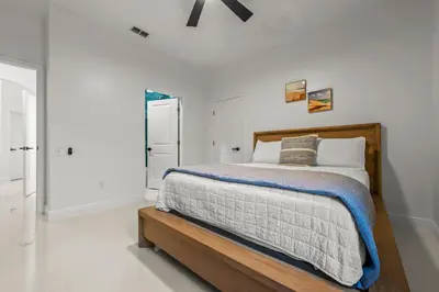 a white bedroom with a bed with a wooden frame at Luxury Disney Retreat in Kissimmee