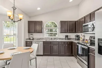 a kitchen with brown cabinets and a wooden table at Magical Family Getaway - 10ppl in Kissimmee
