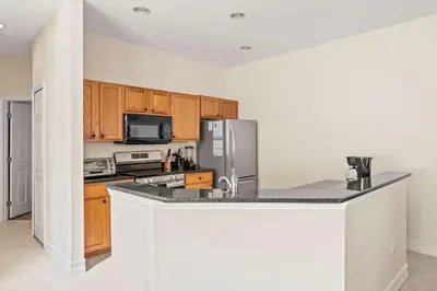 a kitchen with wooden cabinets and a stainless steel refrigerator at Palm Tree in Paradise - 10ppl in Kissimmee