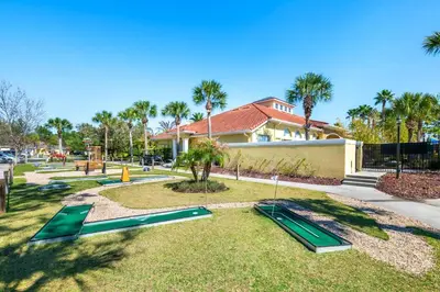 a park with green slides in the grass in front of a house at Palm Tree in Paradise - 10ppl in Kissimmee