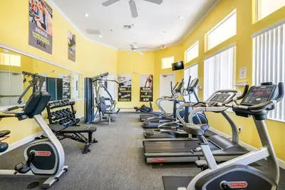 a row of exercise bikes in a gym with yellow walls at Palm Tree in Paradise - 10ppl in Kissimmee