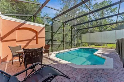 a swimming pool in a glass house with a table and chairs at Palm Tree in Paradise - 10ppl in Kissimmee