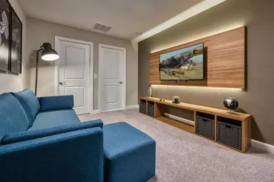 a living room with a blue couch and a tv at Villa 4 Quartos c/ Piscina Perto da Disney + Temas in Orlando