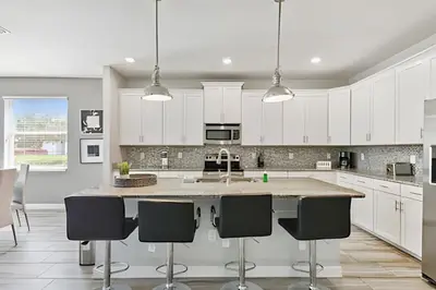 a kitchen with white cabinets and a island with bar stools at Casa Luxo Storey Lake | 6 quartos + Piscina in Kissimmee
