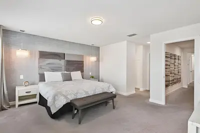 a white bedroom with a large bed and a bench at Casa Luxo Storey Lake | 6 quartos + Piscina in Kissimmee