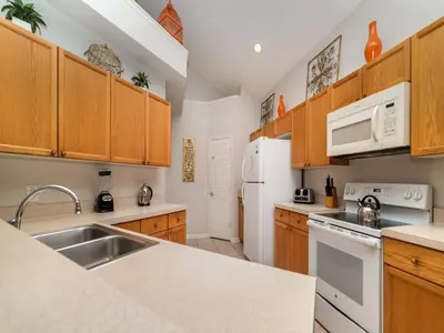 a kitchen with white appliances and wooden cabinets at WP8167SPD – Spacious 6-Bed Oasis with Pool near Disney in Kissimmee