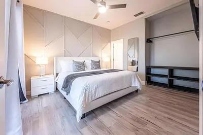 a bedroom with a large white bed and wooden floors at Windsor Hills 4Q c Piscina + Game Room Mario in Orlando