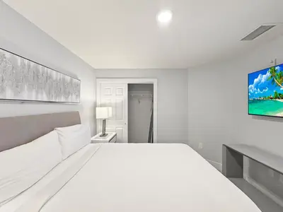 a white bedroom with a large bed and a tv at Modern & Spacious 3 Bedroom Retreat! in Orlando