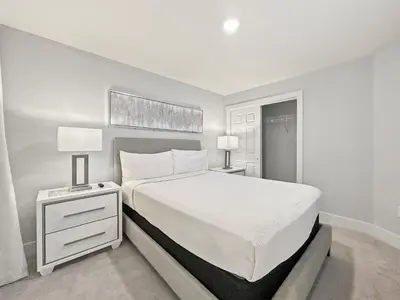 a white bedroom with a large bed and two lamps at Modern & Spacious 3 Bedroom Retreat! in Orlando