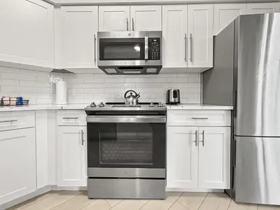 a kitchen with white cabinets and a stove and a microwave at Modern & Spacious 3 Bedroom Retreat! in Orlando