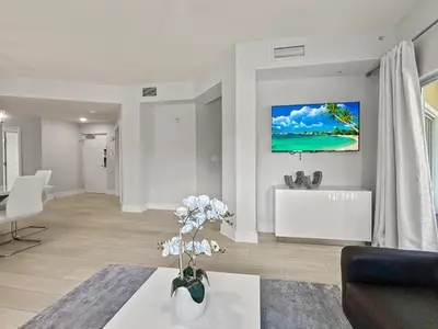 a living room with a couch and a tv on the wall at Modern & Spacious 3 Bedroom Retreat! in Orlando