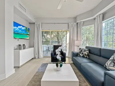 a living room with a blue couch and a table at Modern & Spacious 3 Bedroom Retreat! in Orlando