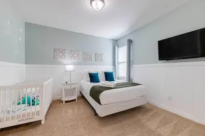 a bedroom with a bed and a tv and a crib at ECR641 8B Stunning Dream Vacation @Encore in Orlando