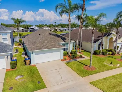 a house with a garage and palm trees at Private Heated Pool near Disney in Kissimmee