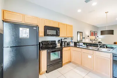 a kitchen with a black refrigerator and a sink at 15min to Disney · Modern Home Hot Tub in Kissimmee