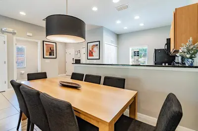 a kitchen and dining room with a wooden table and chairs at 15min to Disney · Modern Home Hot Tub in Kissimmee