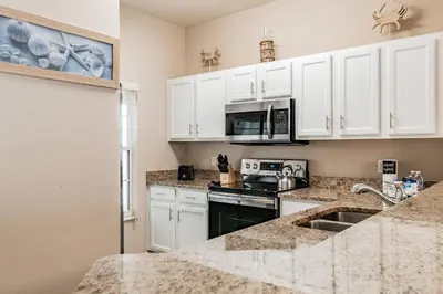 a kitchen with white cabinets and a sink at Family Home Near Disney – Modern Bright in Kissimmee