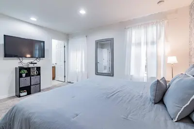 a white bedroom with a large bed and a flat screen tv at 3BR Townhome Near Disney Free Jacuzzi in Kissimmee