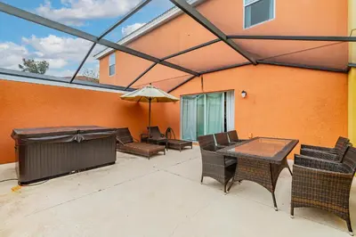 a patio with a table and chairs and an umbrella at 3BR Townhome Near Disney Free Jacuzzi in Kissimmee