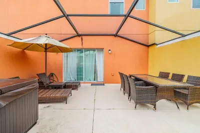 a patio with tables and chairs and an umbrella at 3BR Townhome Near Disney Free Jacuzzi in Kissimmee