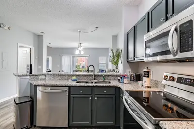 a kitchen with black cabinets and a sink at Cozy 3BR Townhome Near Disney in Kissimmee in Kissimmee
