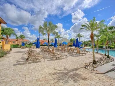 a group of chairs and blue umbrellas next to a pool at Cozy 3BR Villa 15min from Disney Heated Pool in Kissimmee