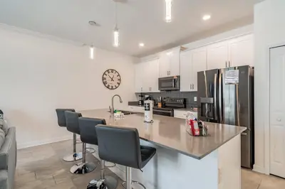 a kitchen with a counter with chairs and a refrigerator at Disney 15min - Private Pool BBQ in Kissimmee