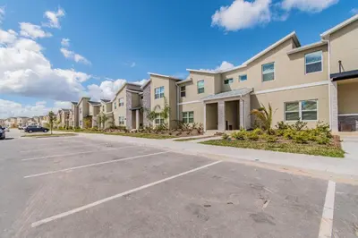 a row of apartment buildings in a parking lot at Disney 15min - Private Pool BBQ in Kissimmee