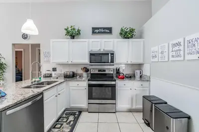 a kitchen with white cabinets and stainless steel appliances at Lake Berkley Getaway – 5BR Resort Home in Kissimmee