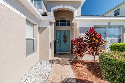 a house with a blue door and some plants at Lake Berkley Getaway – 5BR Private Pool in Kissimmee