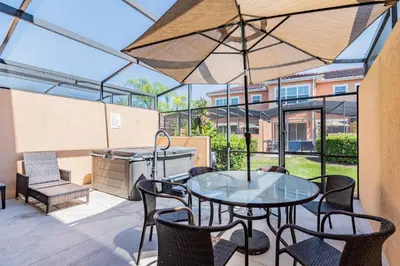 a patio with a table and chairs and an umbrella at 2BR Villa Near Disney Resort Amenities in Kissimmee
