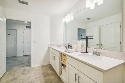 a white bathroom with a sink and a mirror at Luxury Resort · Pool Lazy River in Kissimmee