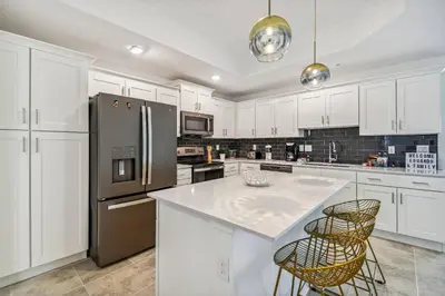 a kitchen with white cabinets and a stainless steel refrigerator at Luxury Resort · Pool Lazy River in Kissimmee