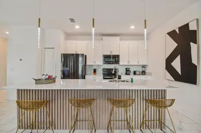 a kitchen with a counter with three bar stools at Disney Retreat · Pool Themed Bedrooms in Kissimmee