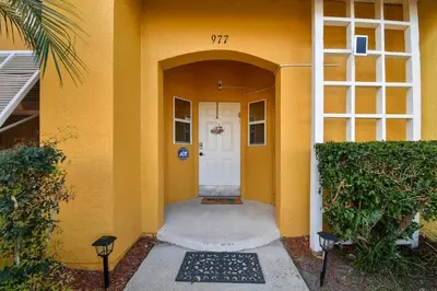 a front door of a house with a yellow wall at Family Stay Close to Disney Parks in Kissimmee