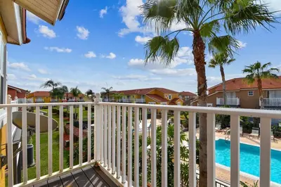 a balcony with a view of the pool and palm trees at Family Stay Close to Disney Parks in Kissimmee