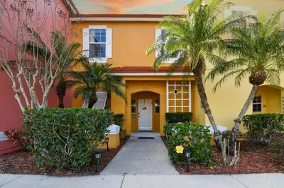 a yellow house with palm trees in front of it at Family Stay Close to Disney Parks in Kissimmee