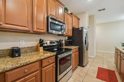 a kitchen with wooden cabinets and a stove and refrigerator at Orlando Getaway w Heated Pool in Kissimmee