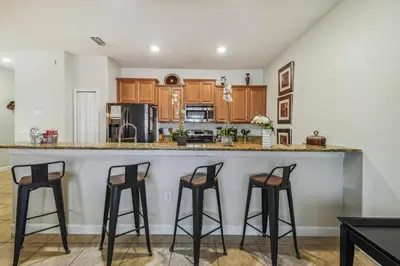 a kitchen with three bar stools at a counter at Disney Retreat – 15min to Parks in Kissimmee