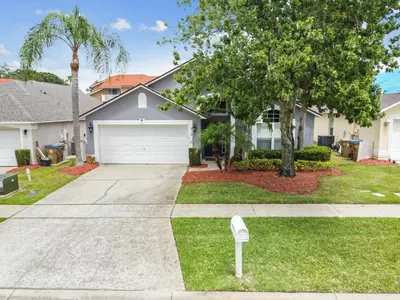 a house with a driveway and a tree at Family Retreat near Disney in Kissimmee